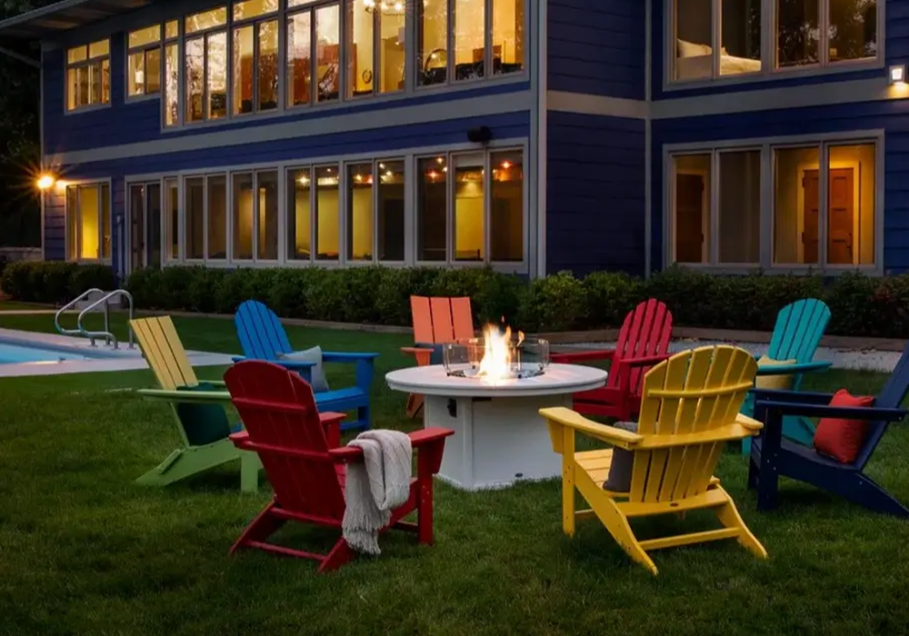 Colorful Adirondack chairs surrounding a fire pit beside a pool, creating a welcoming outdoor gathering space for guests.